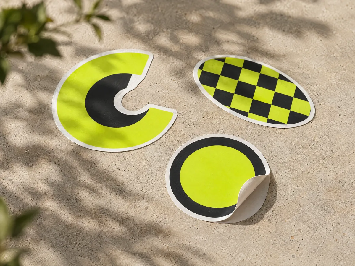 White vinyl die cut stickers with a bold printed design on a stone surface.